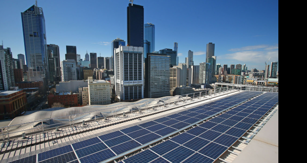 Commercial rooftop solar array with city skyline in background